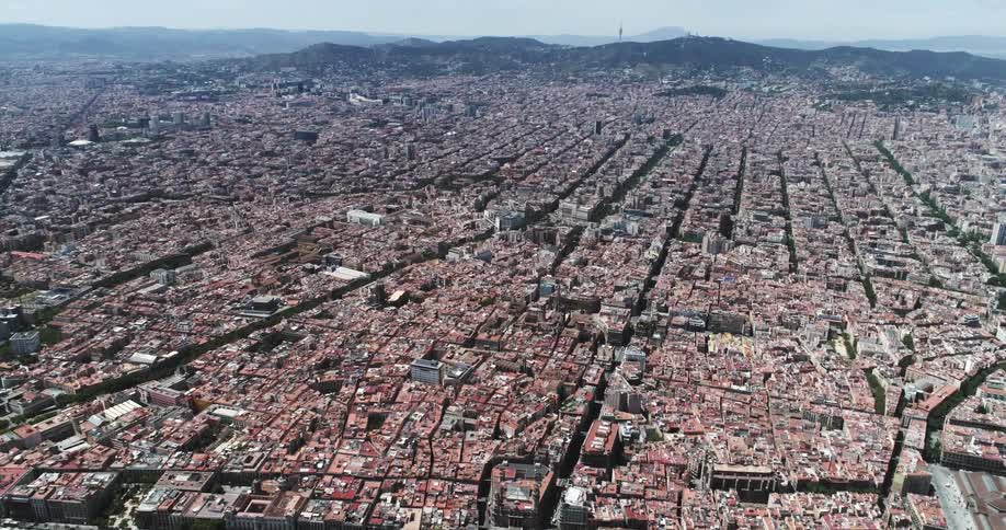 An aerial of a dense metropolitan city with many buildings and mountains in the distance