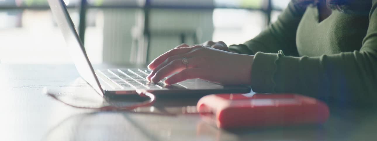 A woman is sitting at a desk with her laptop
