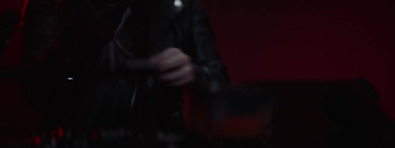 Person in warehouse or garage putting on gloves and motorcycle gear standing in front of a motorcycle