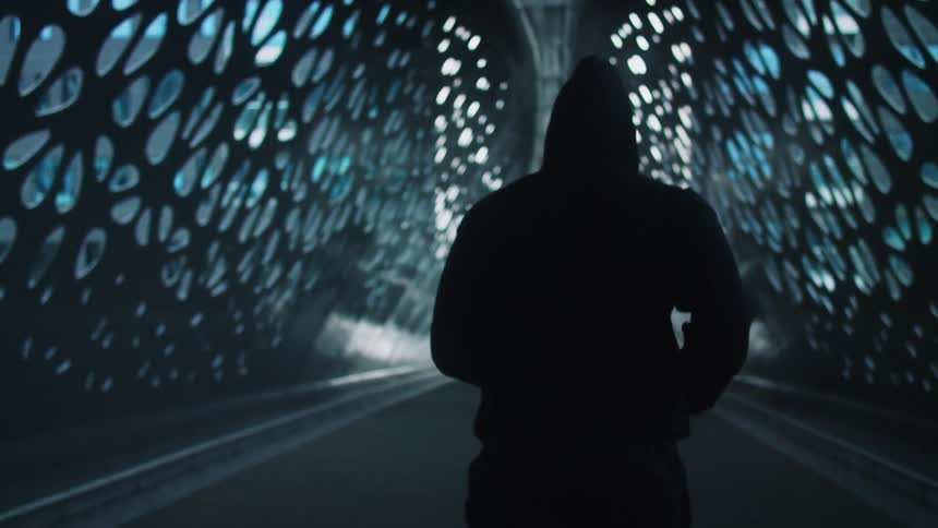 Man with hoodie and pants jogs across bridge