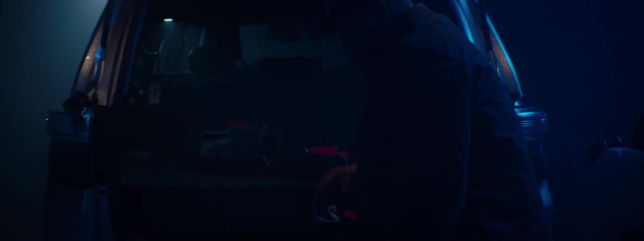 Nighttime man packing gear into the back of an suv