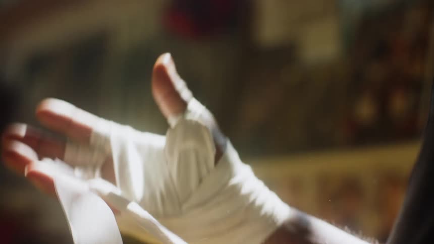 A close up of a person wrapping their hands through the fingers with a white wrap