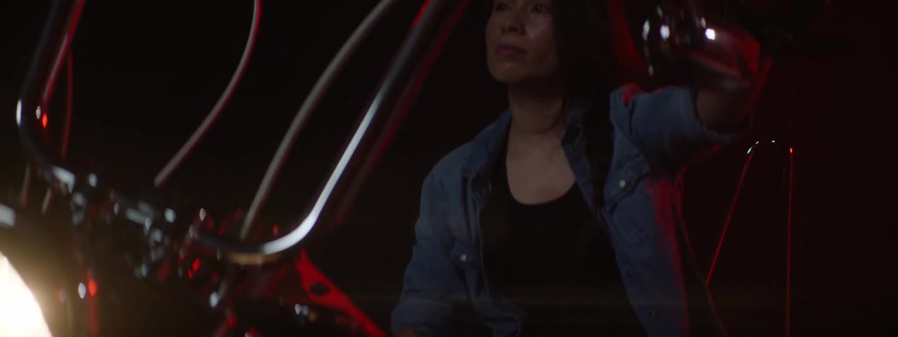 A woman is getting on her motorcycle during the night time