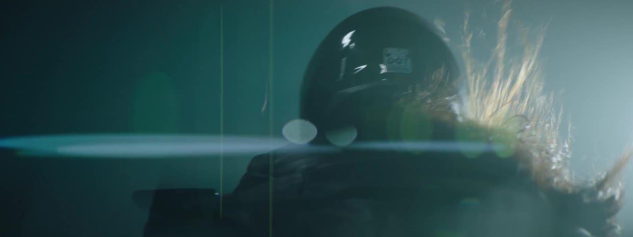 A female motorcyclist wearing a helmet races along a road at night