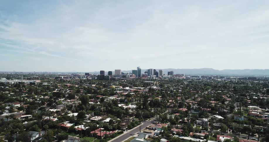 Towers and skyscrapers stand tall overlooking a large metropolitan city surrounded by suburbs with mountains on the horizon