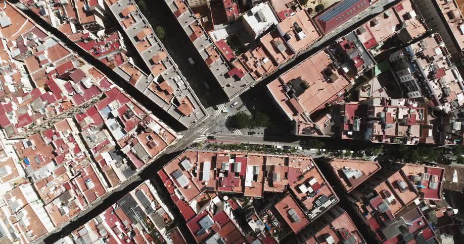 A straight down aerial of a city intersection with buildings close together and cars on the street