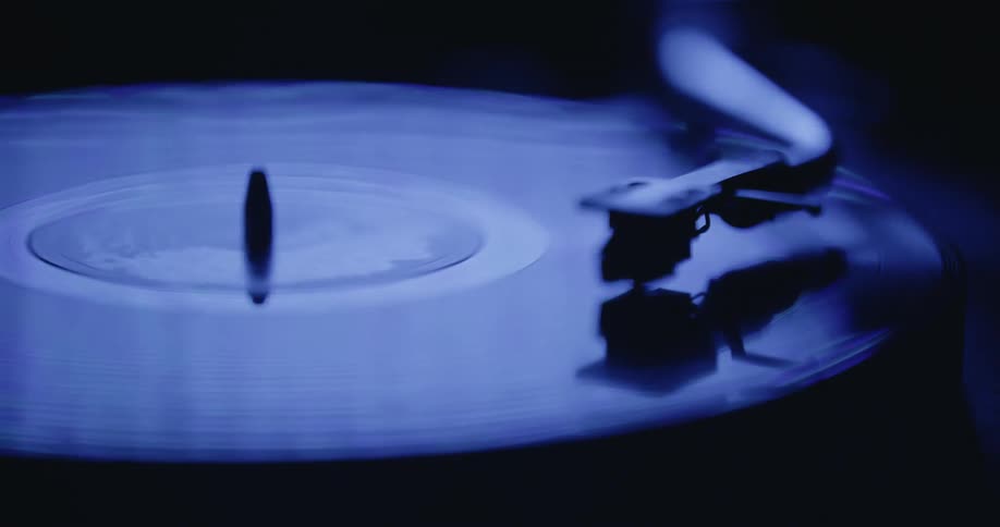 A close up of spinning vinyl on a record player as the ambient light changes color