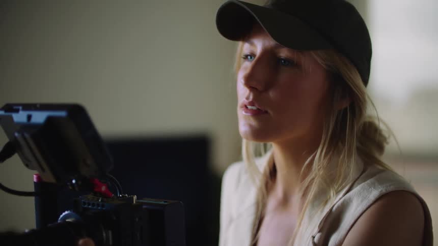 A woman looks at the display on her digital camera as she makes adjustments