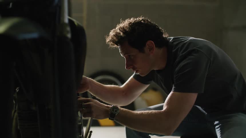 A man works on his motorcycle in a parking garage