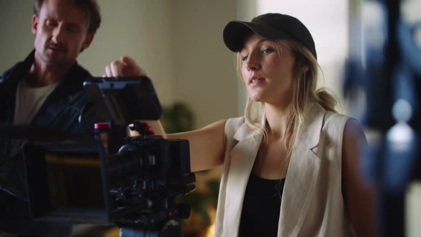 A female director looks away from her camera in order to guide a colleague