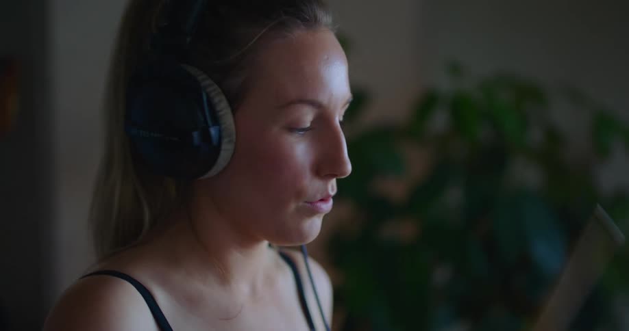 Female drummer wears headphones while playing drums in home