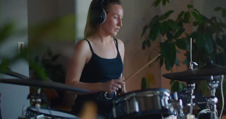 Woman wearing headphones plays drums