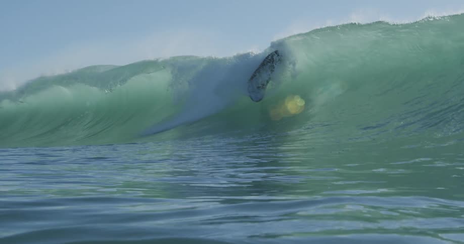 A man on a surfboard riding a wave rolling over him in the ocean