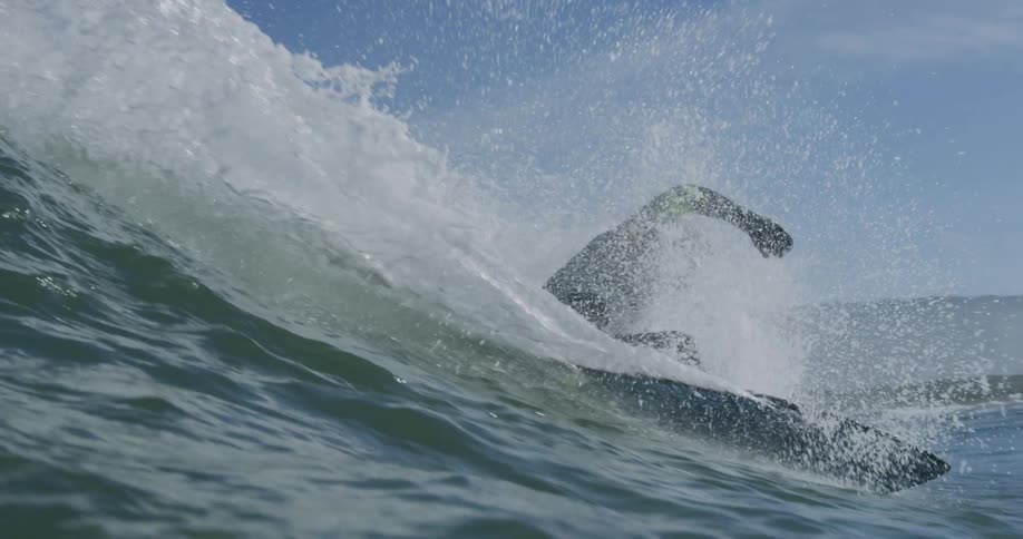 Man in black wetsuit surfs waves off the coast