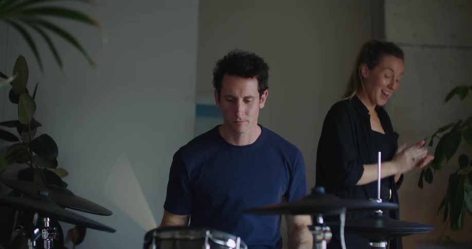 A woman claps along while a man plays the drums