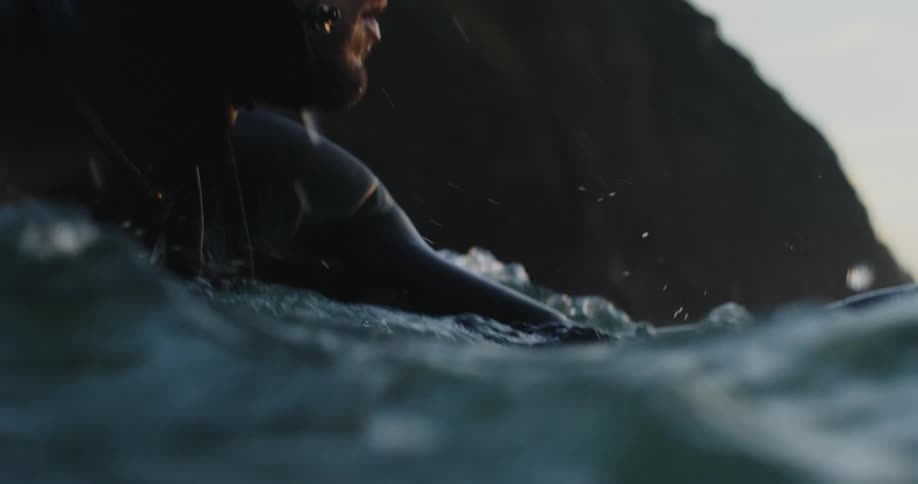 Man with black wetsuit on surfboard in ocean water surfing