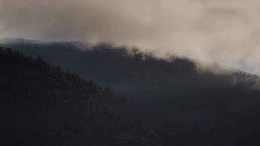 A time lapse of fog rolling over hills full of forests