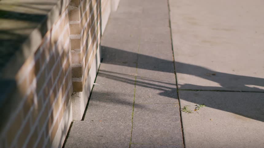 A close up of a persons feet and a tote bag they are carrying as they walk away