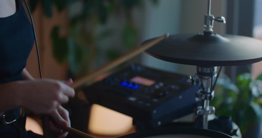 A woman wears headphones while playing the drums