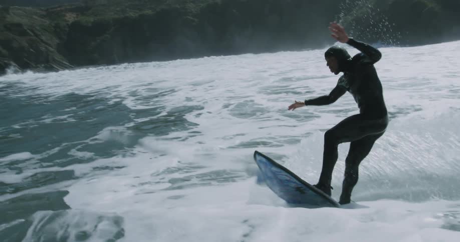 Man in wetsuit rides wave on surfboard