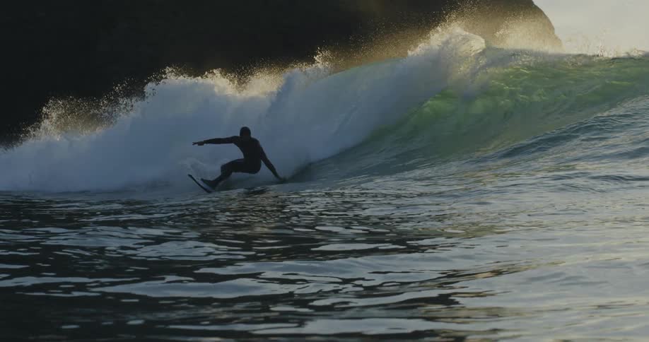 Waves crashing on the ocean as a person on a surf board rides them