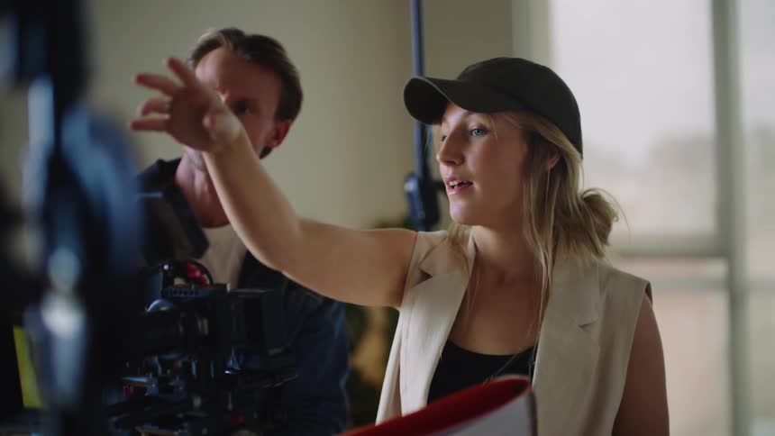 A woman directs a video from behind the camera