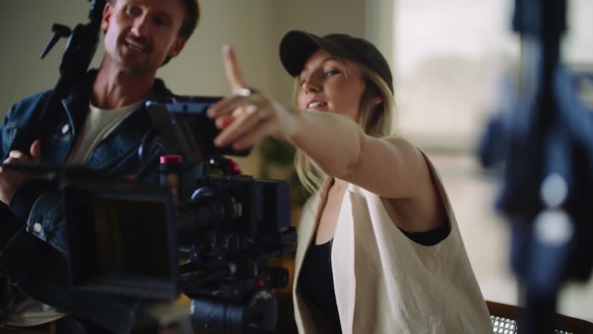 Female film director wearing black hat and brown vest tells the actors and staff what to do
