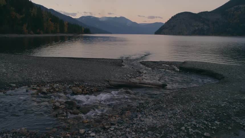 Stream flows to lake surrounded by forested mountains
