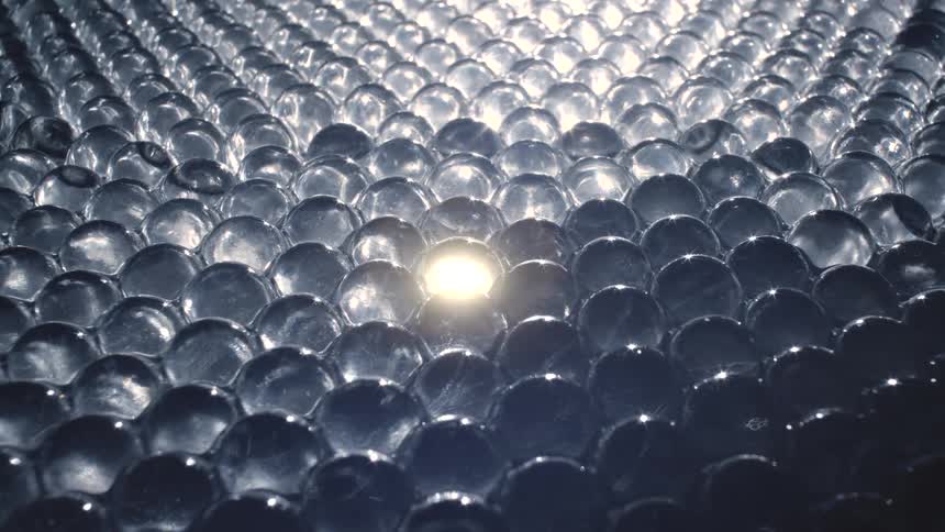 The sun shines and reflects on clear water beads
