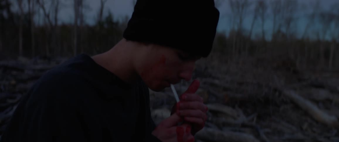 A man is standing in the woods smoking