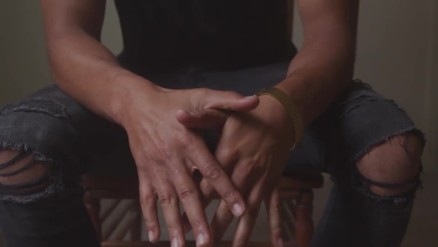 A man folds his hands sitting on a chair