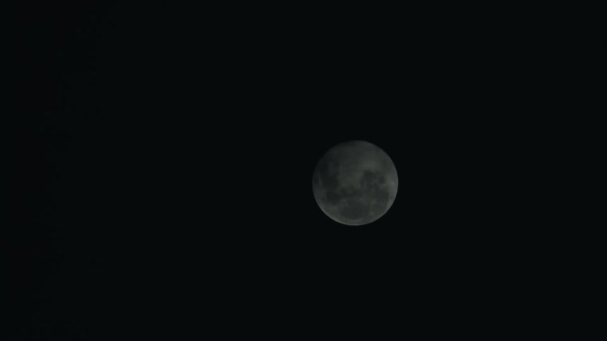 Full moon in the nighttime sky low visibility of stars with fog or clouds moving across and obscuring the moon
