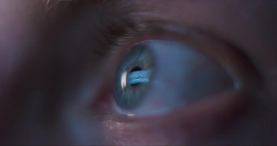 Flashing light from a television reflects on a persons eye