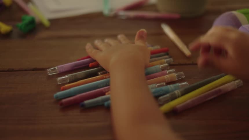 Person bends back her fingers after using both hands to line up coloring pens