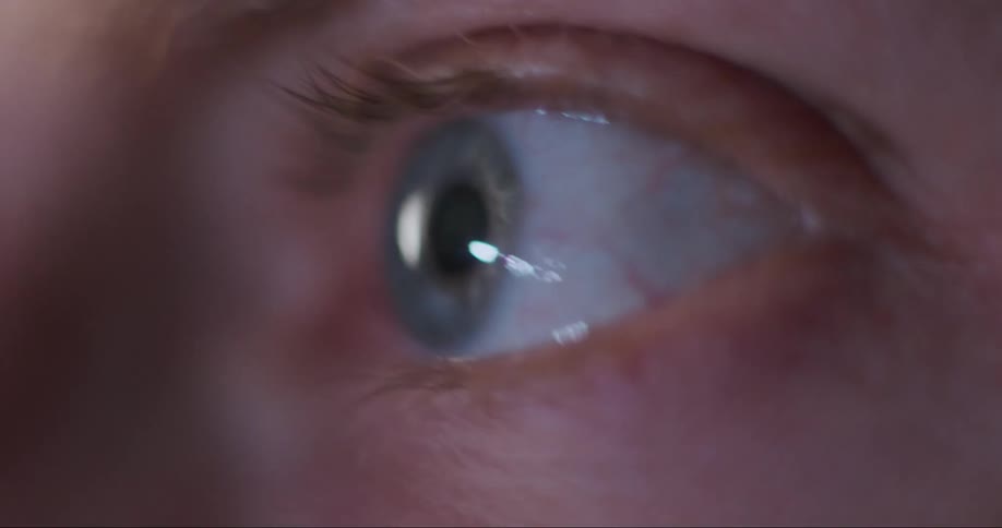 Light shines and reflects on a persons eyeball and they occasionally blink