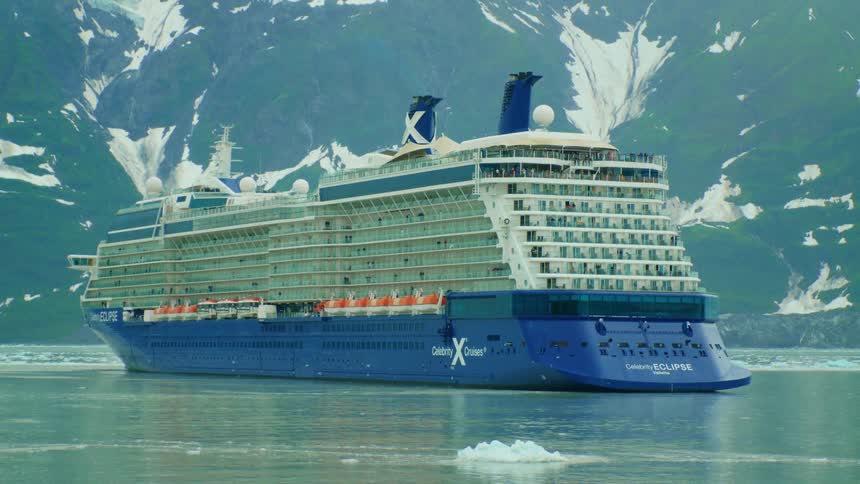 Large ferry sailing over a lake surrounde by ice chunks near the mountains at daytime