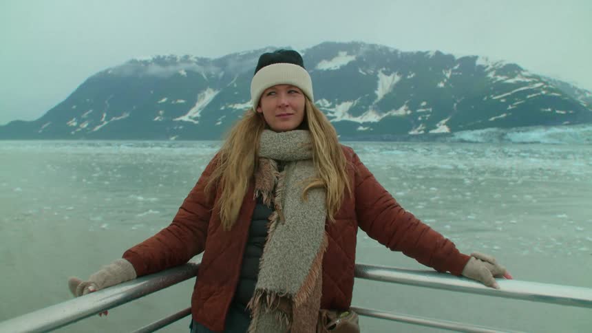 A woman stands against the railing on a boat