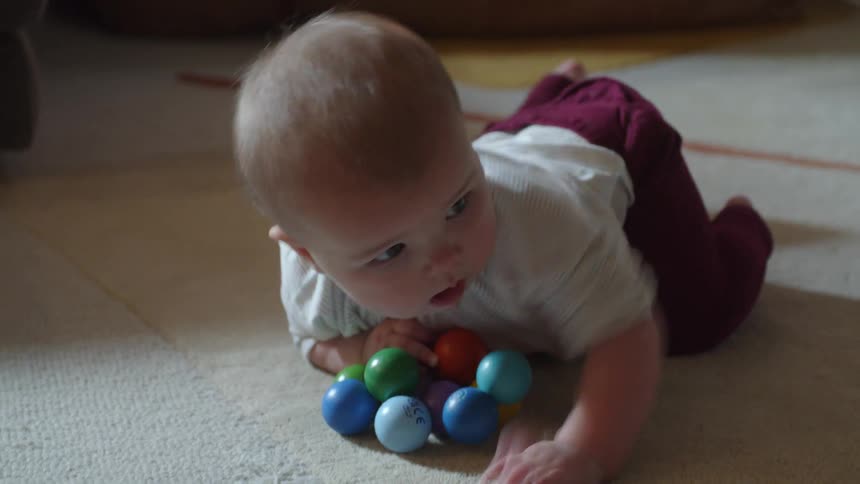 A young baby laying on a white carpet attempting to lift herself off the floor