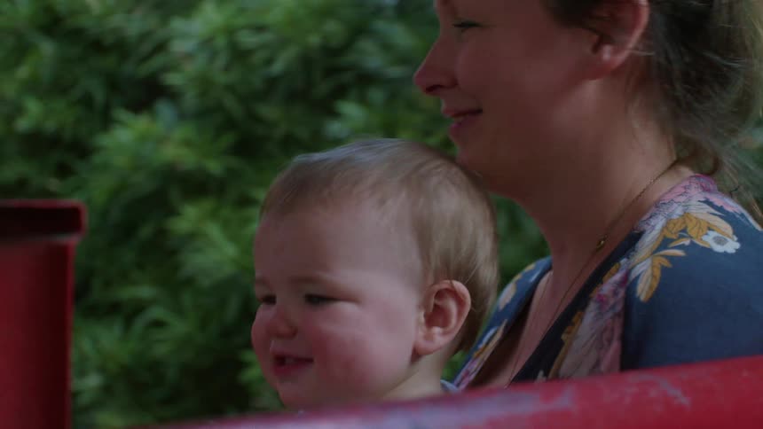 A mother and her baby ride happily on a novelty train