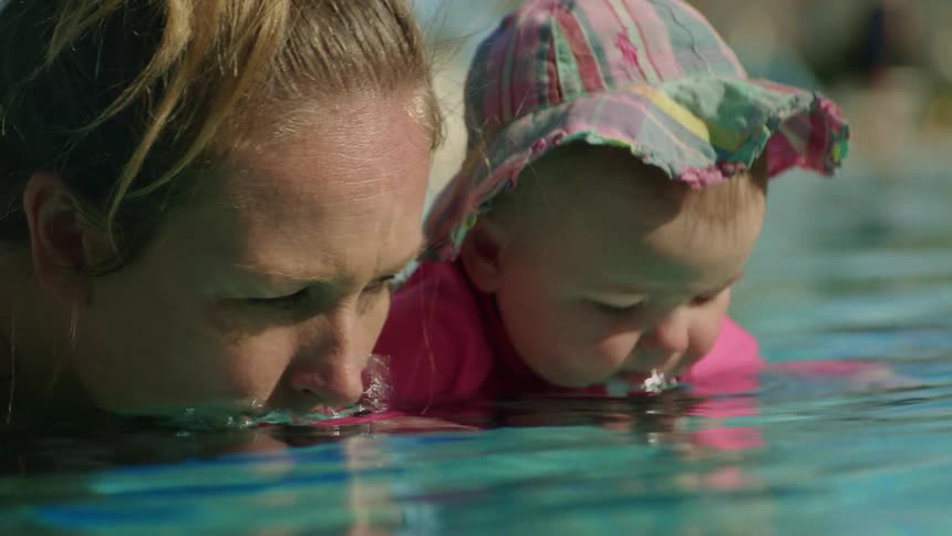 Blonde mother and baby swimming in the pool