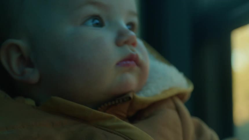 Blonde mother wearing wooly hat and coat holds baby and kisses his head