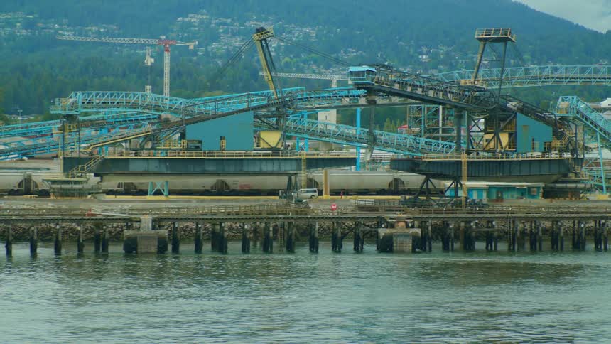 A cargo van drives along a pier at a shipping port