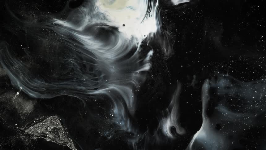 Abstract closeup of black and white paint liquids and oil with some glitter and some movement