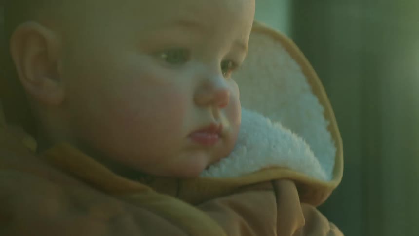 Close up of a mother sitting on a moving vehicle holding a baby on her lap