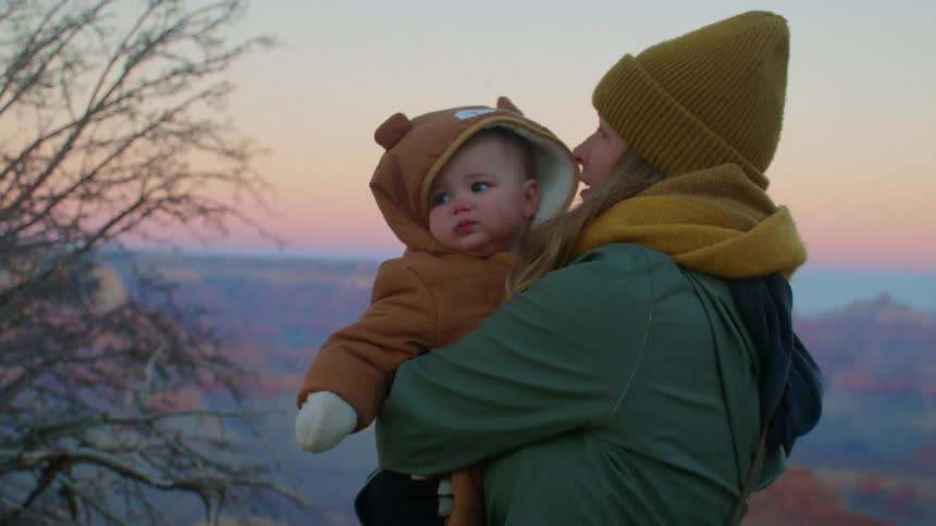 Mother is hiking with her daughter at sunset