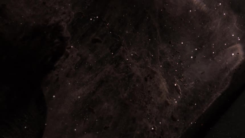 Abstract closeup of liquids probably paints black and white with gray and specks of white moving slowly looks cosmic