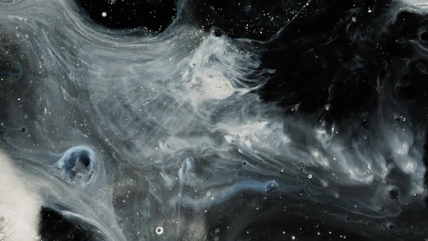 Black and white liquid swirls moving around on a surface