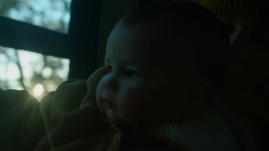 A woman sitting in a passenger seat of an automobile holds her baby as they travel on the road