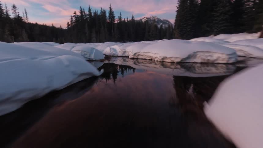 FPV drone shot of a large body water with patches of snow covered ice