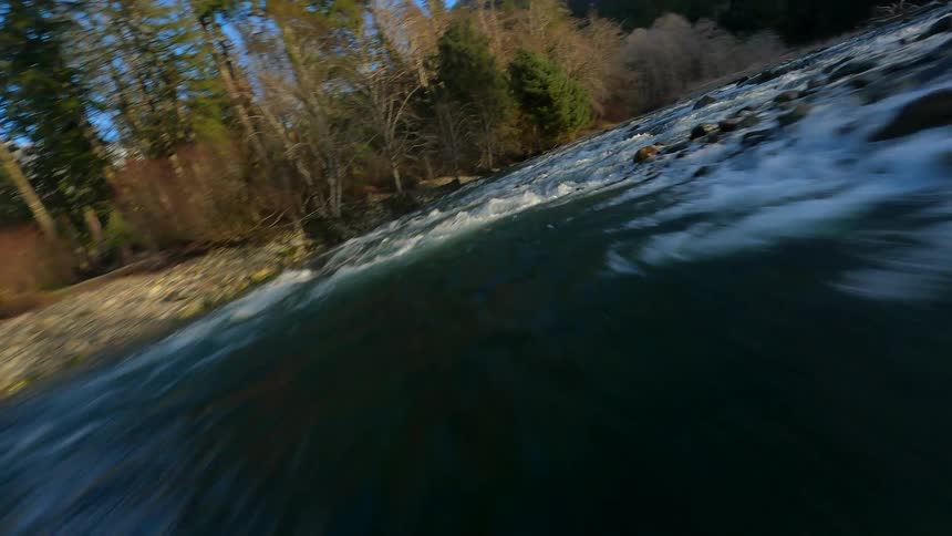 An FPV drone shot flying over a river